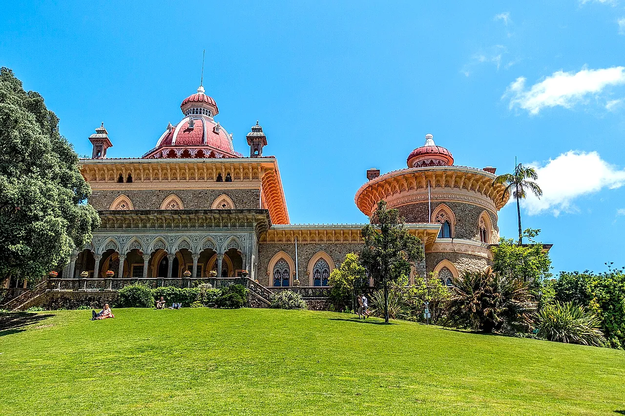 Der Monserrate-Palast mit rosa Kuppeln und Arkaden über einer leuchtend grünen Wiese