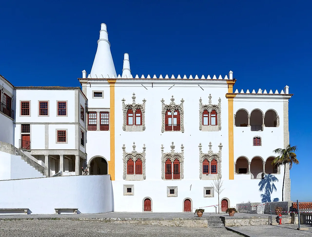 La fachada blanca del Palacio Nacional de Sintra con sus dos chimeneas cónicas de cocina y ventanas manuelinas