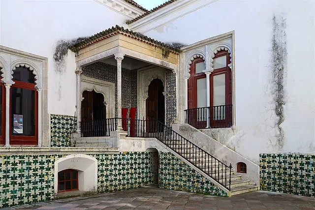 Een betegelde loggia en binnenplaats van het Nationaal Paleis van Sintra met ramen in Moorse stijl