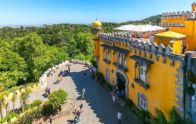 Het gele terras van het Paleis van Pena met kantelen en bogen boven de groene heuvels van Sintra