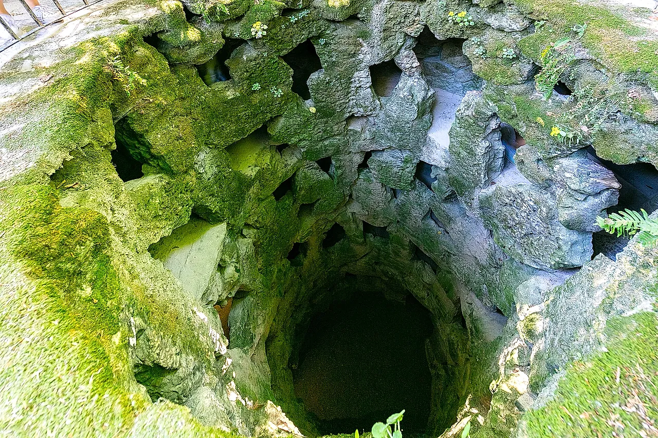 Blick hinab in den Initiationsbrunnen der Quinta da Regaleira mit seinen moosbewachsenen Spiralwänden